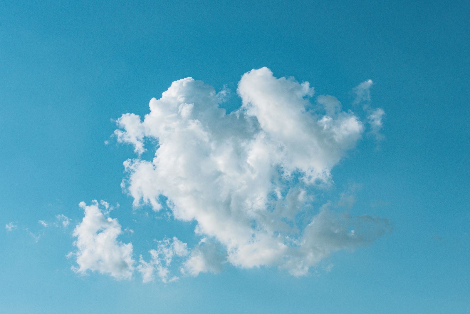 A calm blue sky with a single soft white cloud