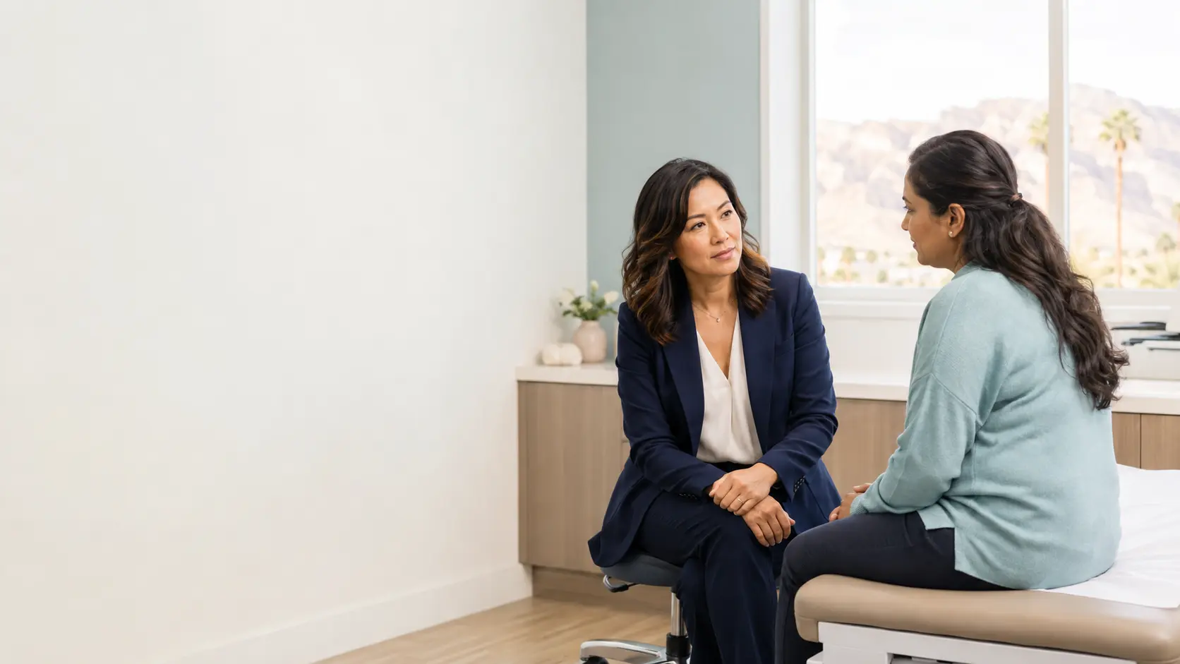 A healthcare clinician listening attentively to a patient in a bright consultation room